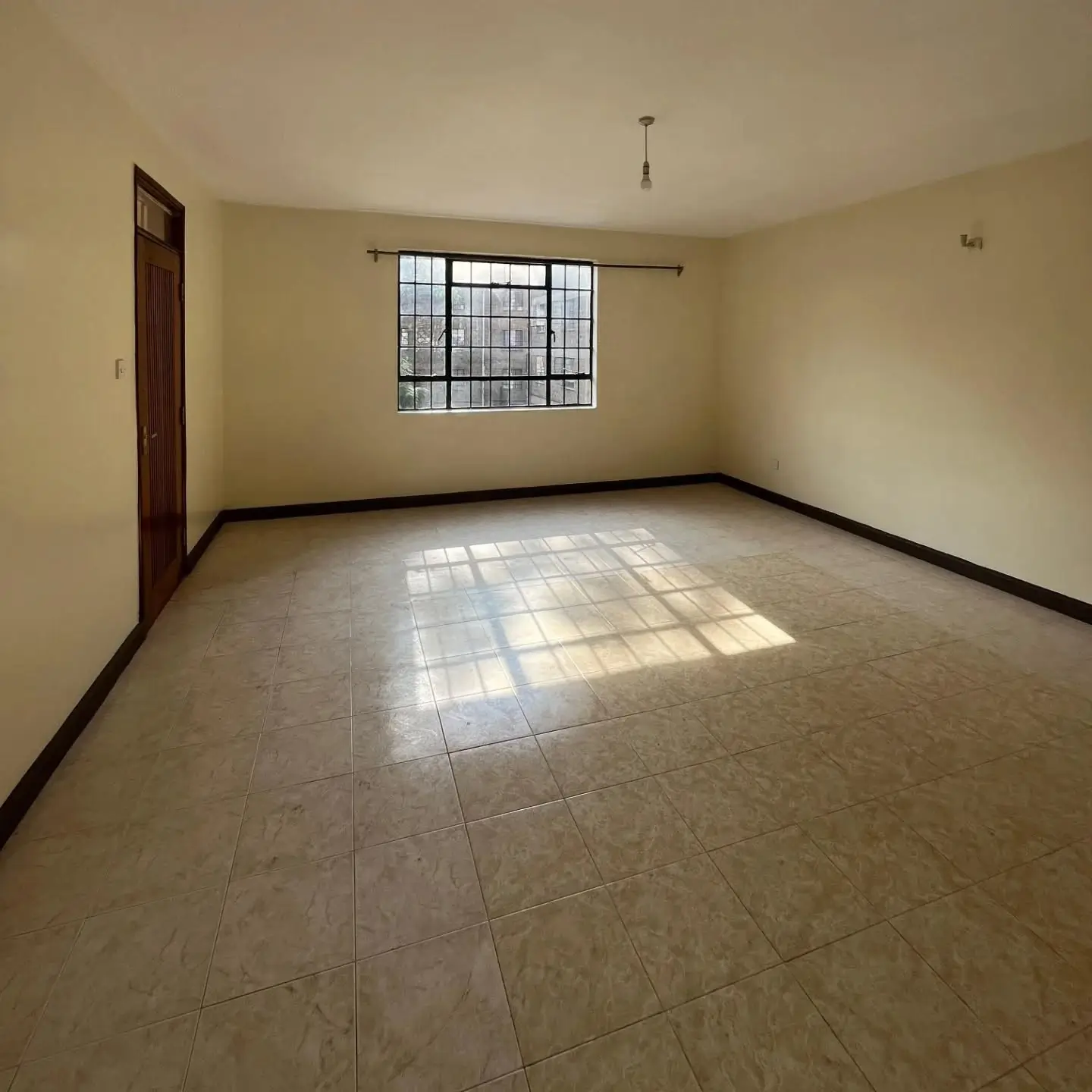 Spacious empty bedroom with tiled floor and barred window