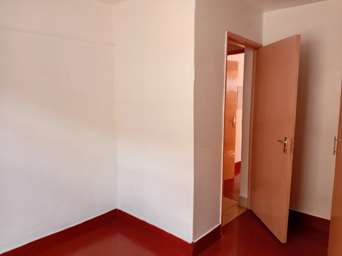 Empty bedroom with red floor and open doorway