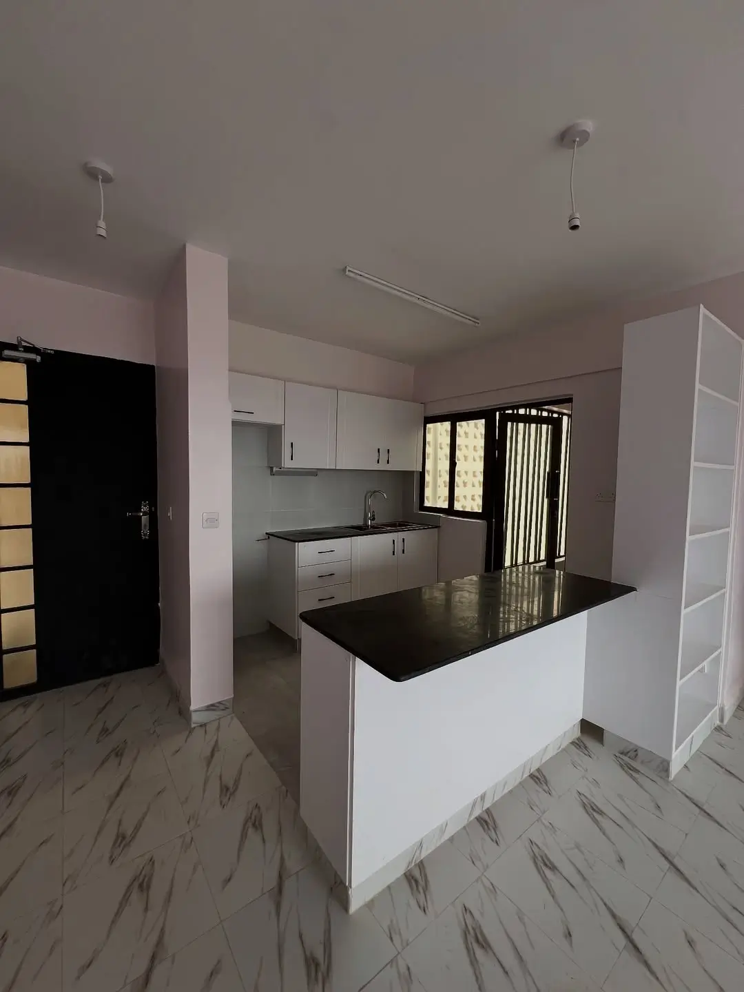 Open-plan kitchen with black island countertop and white cabinetry