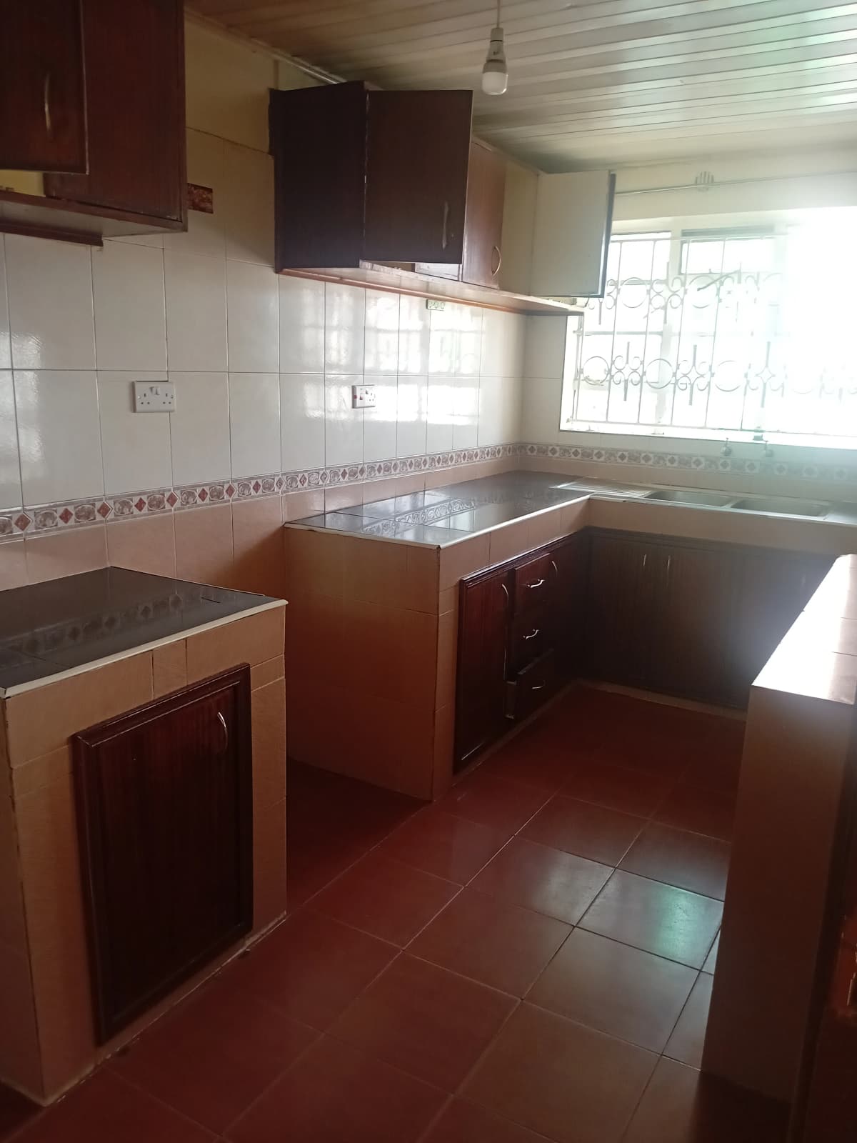 L-shaped kitchen with dark wood cabinets, tiled backsplash