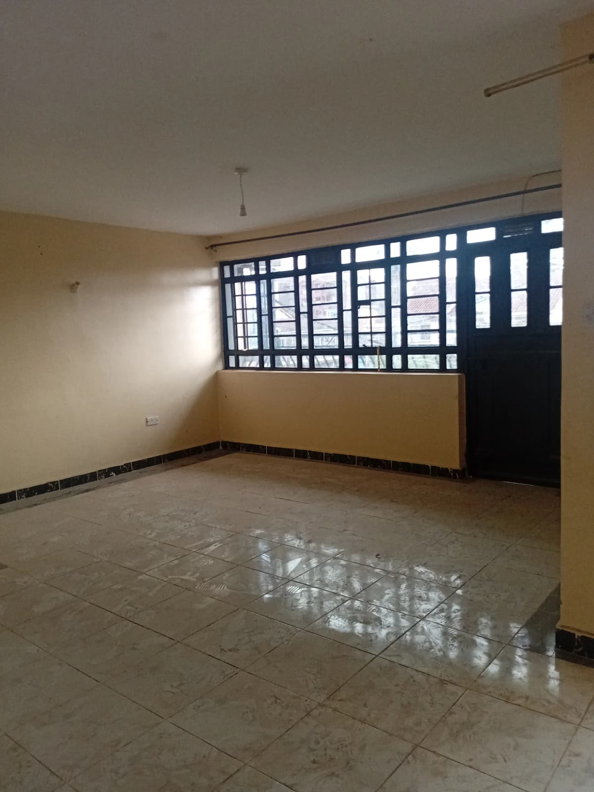 Spacious living room with large barred windows and tiled flooring