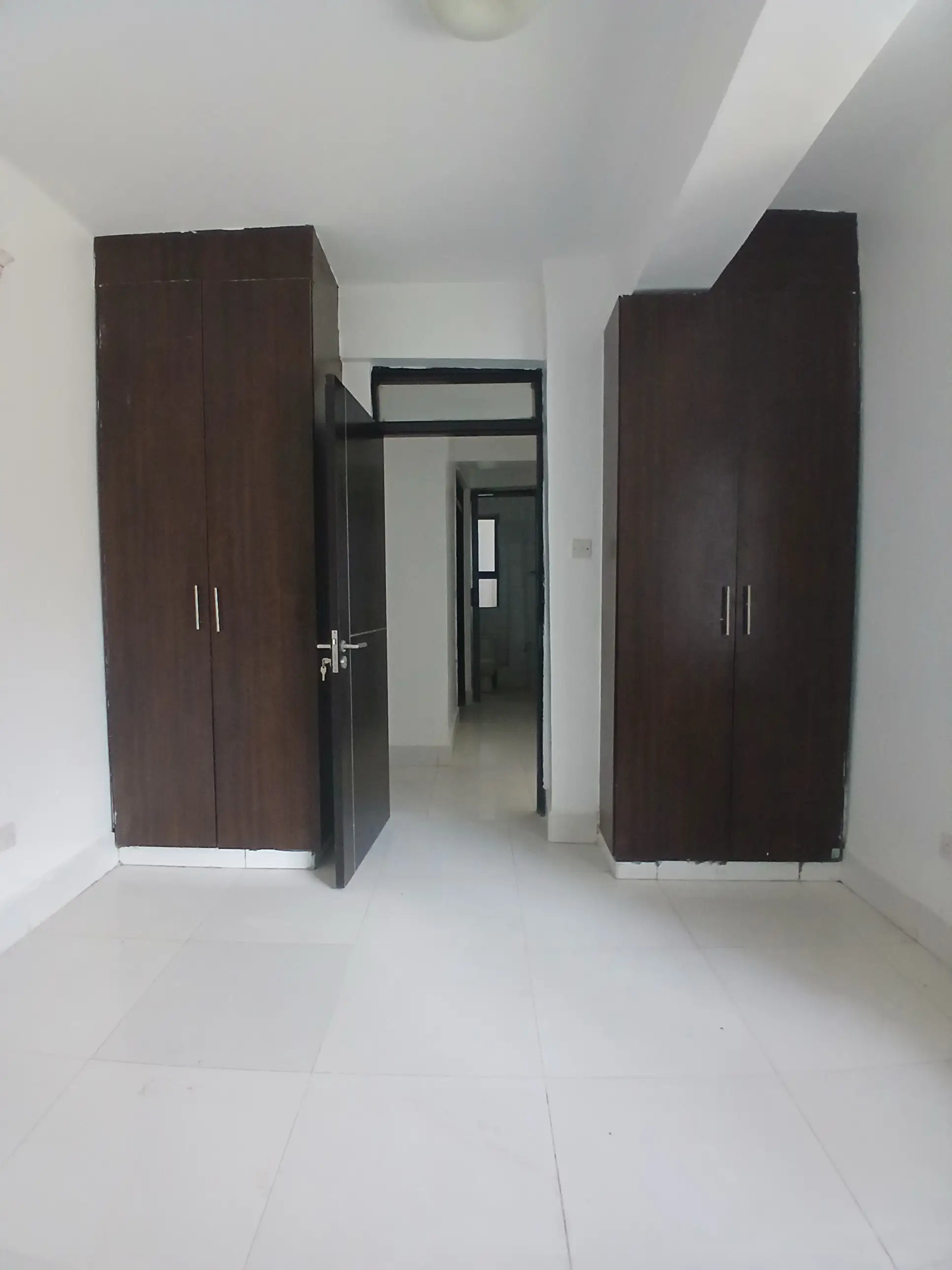 Unfurnished bedroom with built-in dark wood wardrobes