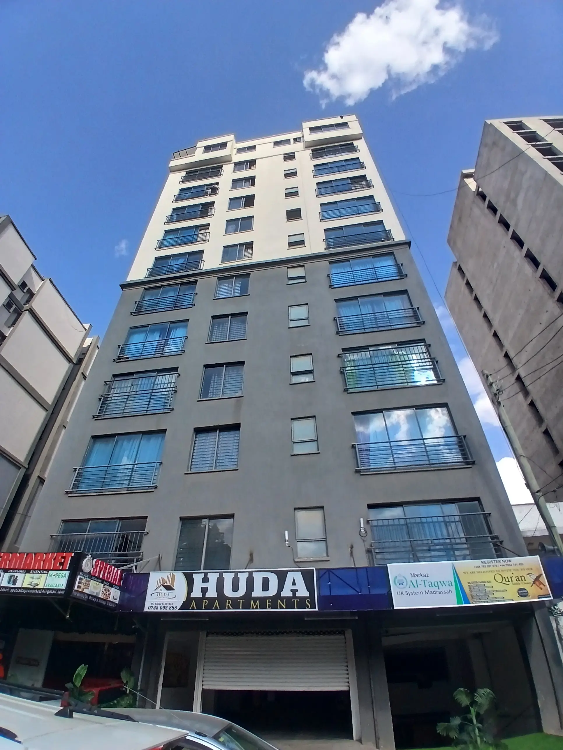 Modern multi-story residential building with balconies and ground-floor shops