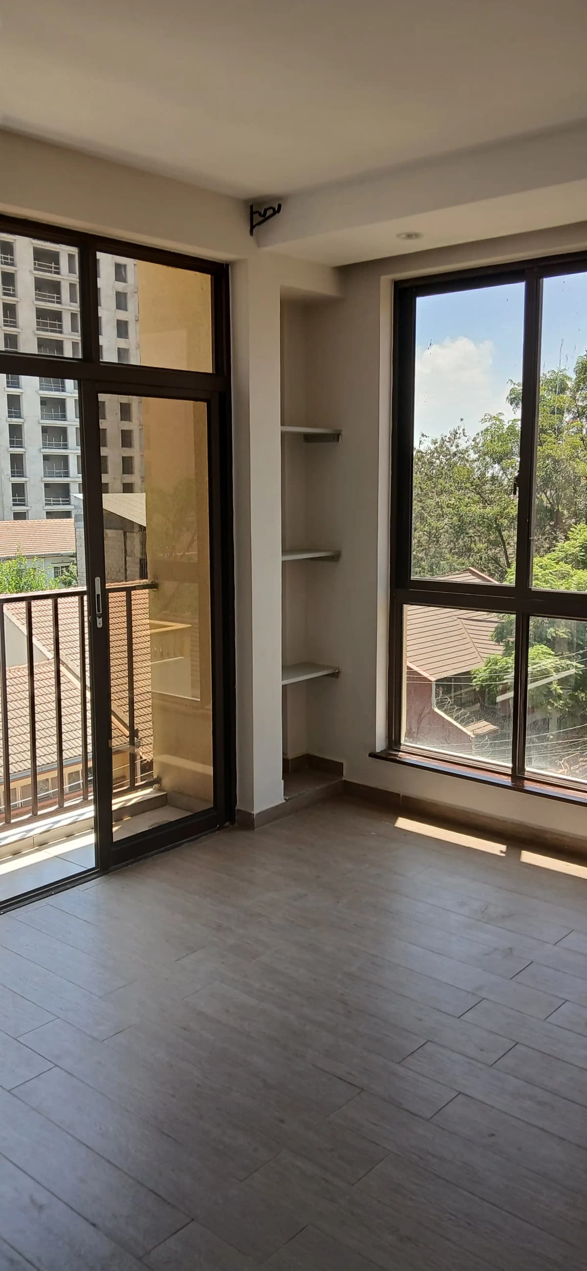 Spacious balcony with glass doors and tree views