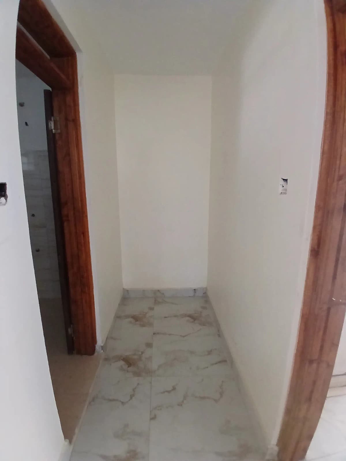 Narrow hallway with wooden door frames and concrete flooring