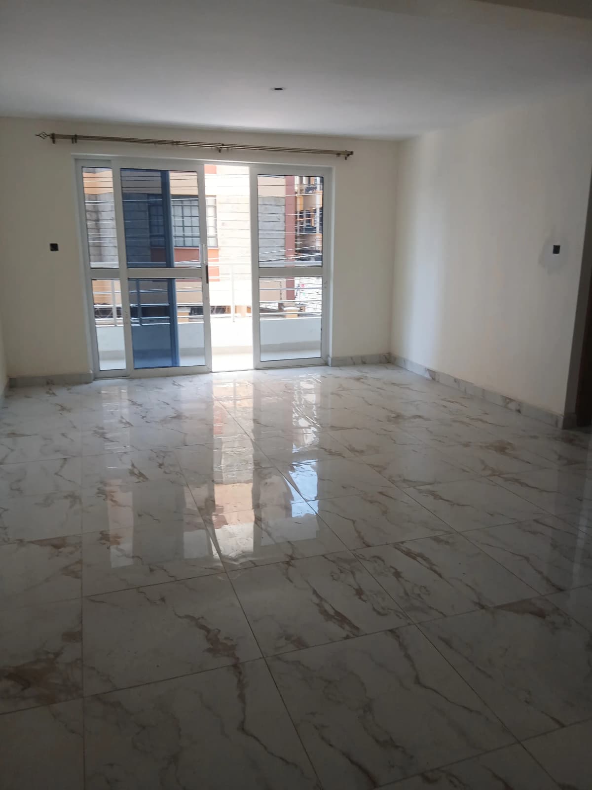 Spacious empty living room with marble flooring and glass doors