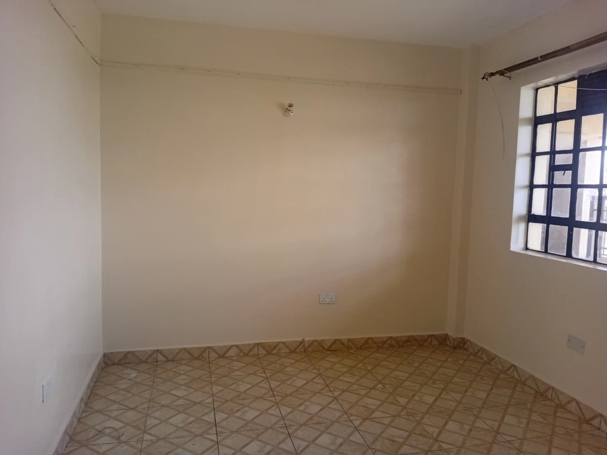 Empty bedroom with terracotta tile floor and window light