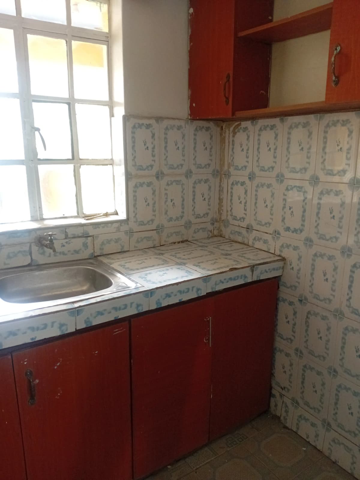 Compact kitchen with red cabinetry and patterned tile backsplash