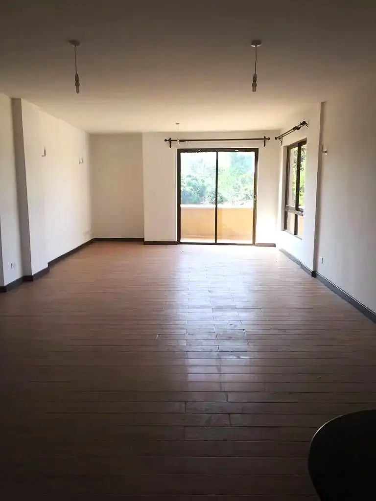 Spacious living room with wooden flooring and glass balcony doors