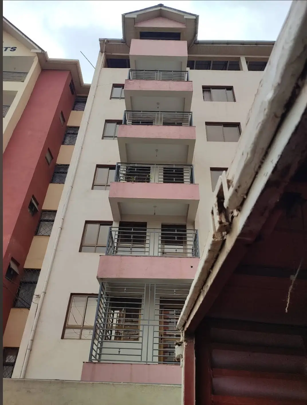 Multi-story residential building facade with pink and cream trim