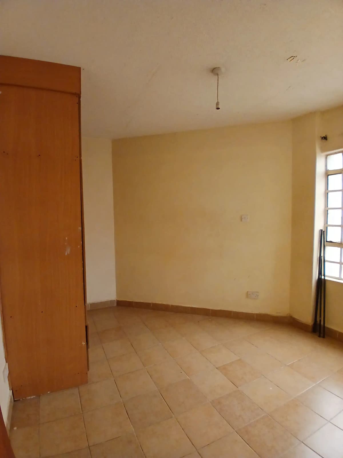 Empty bedroom with wooden door and tiled flooring