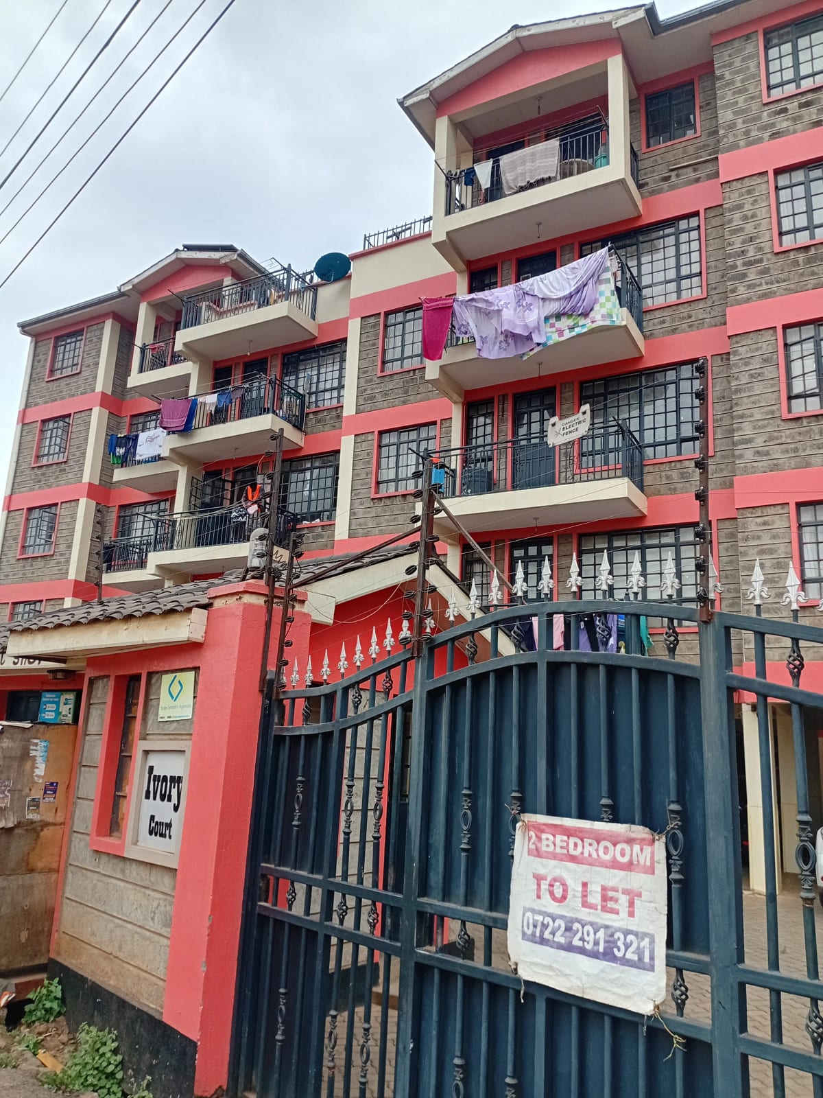 Multi-story residential building with red facade and metal gate