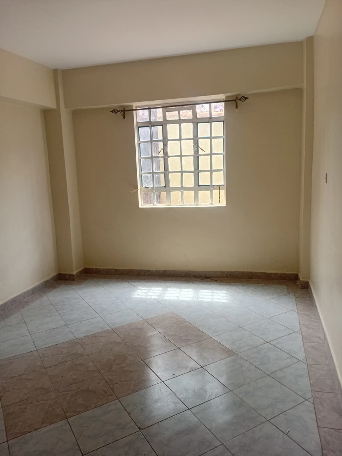 Spacious bedroom with tiled floor and barred window