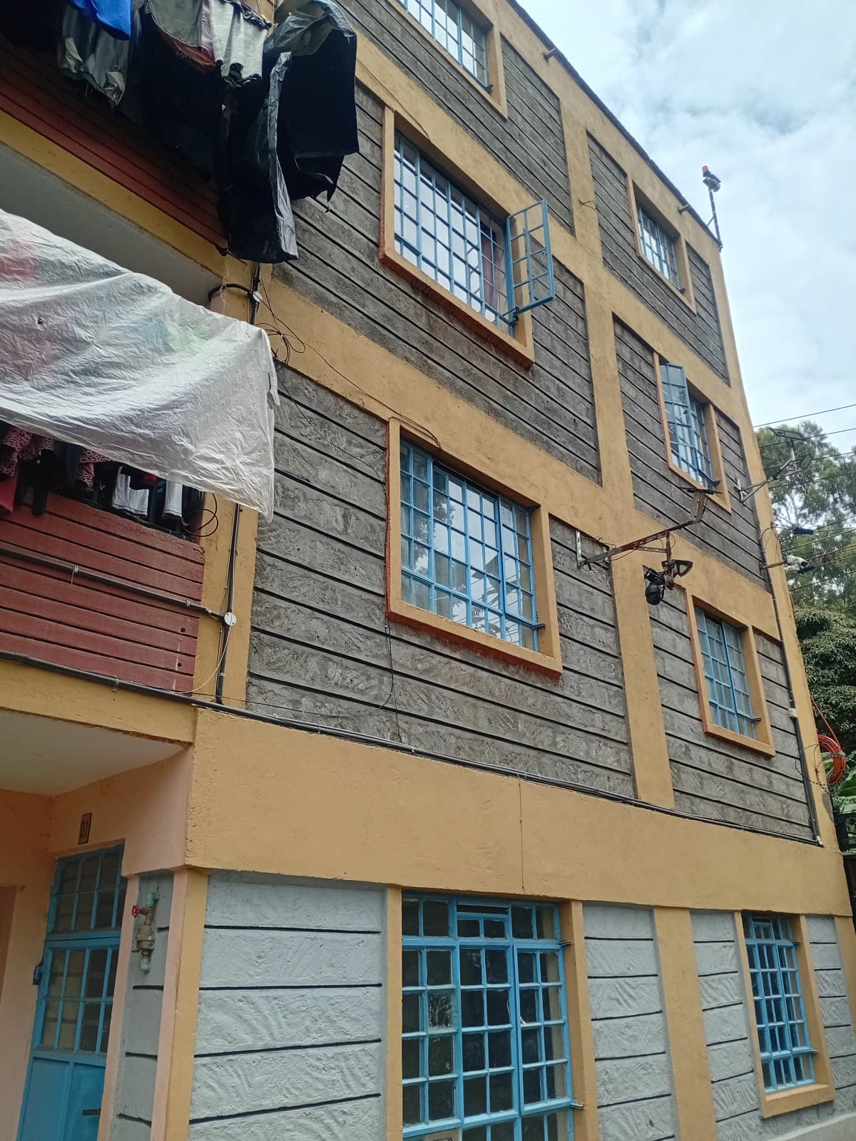 Multi-story residential building facade with yellow and gray finish
