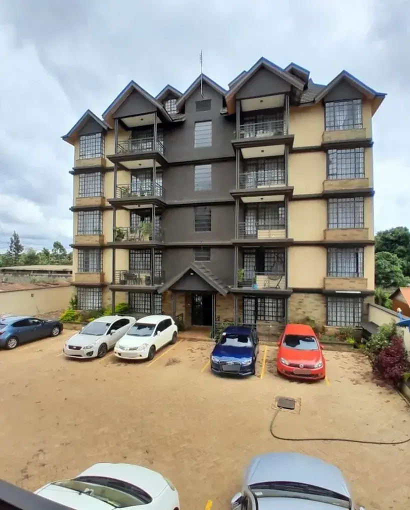 Multi-story residential building facade with ground-level parking compound