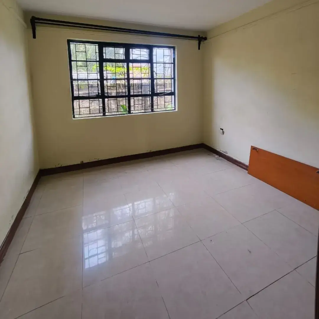 Empty bedroom with large window and polished tile flooring