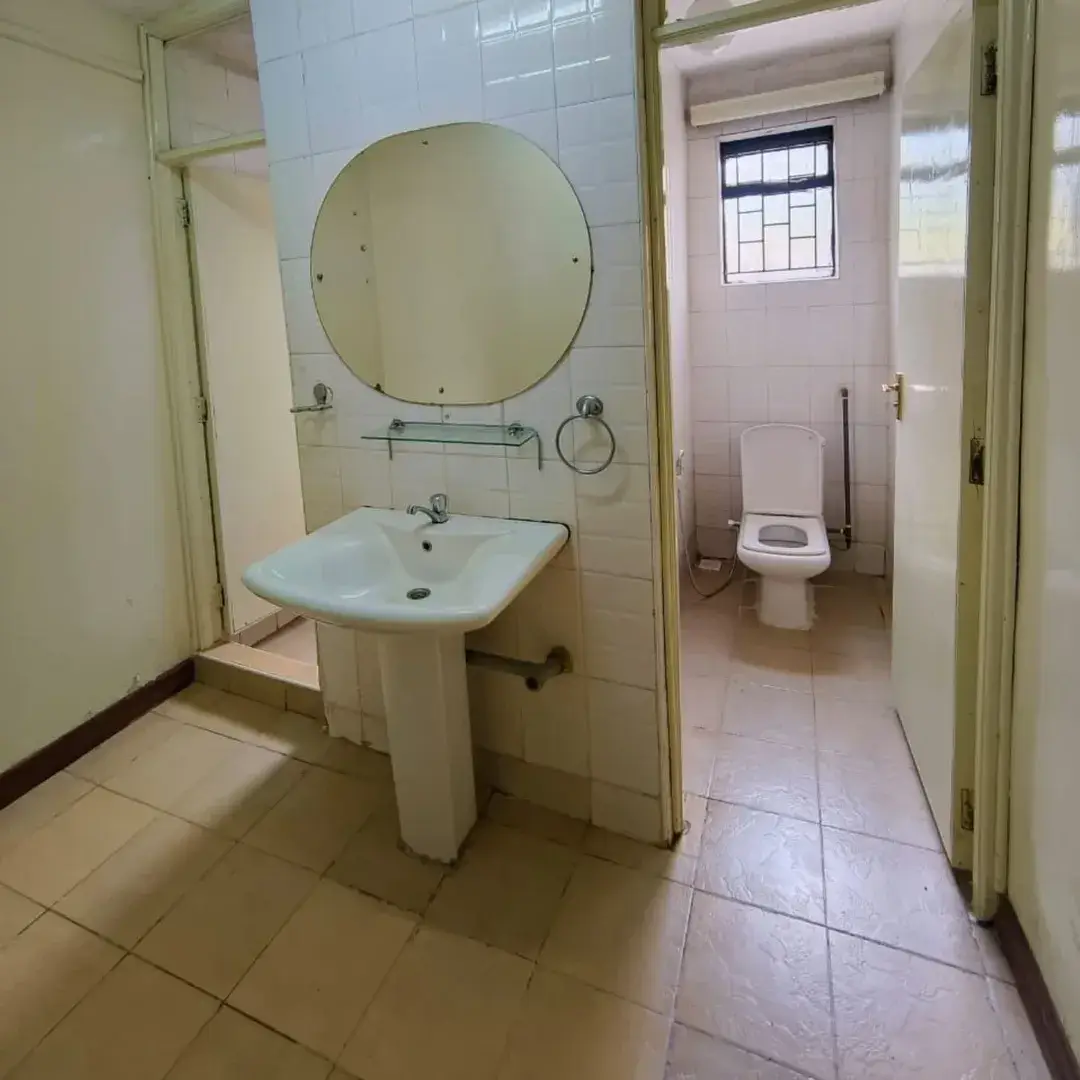 Bathroom with pedestal sink, large mirror, and toilet visible