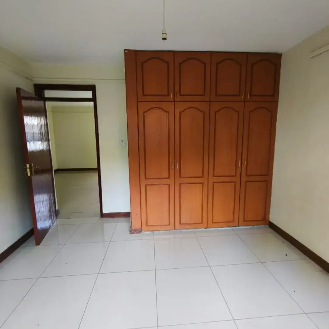 Spacious bedroom with large wooden wardrobe and tiled floor