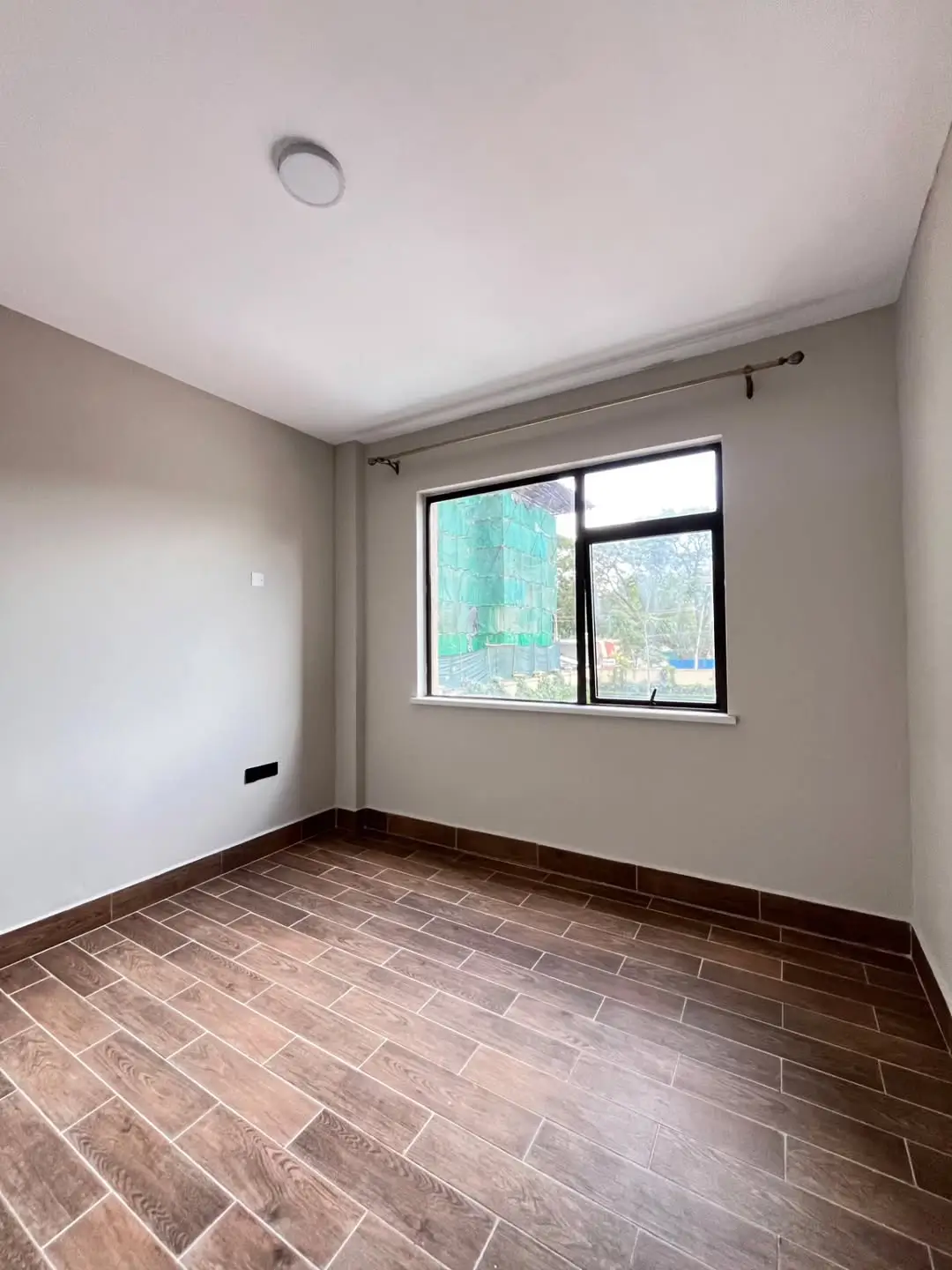 Empty bedroom with herringbone flooring and large window