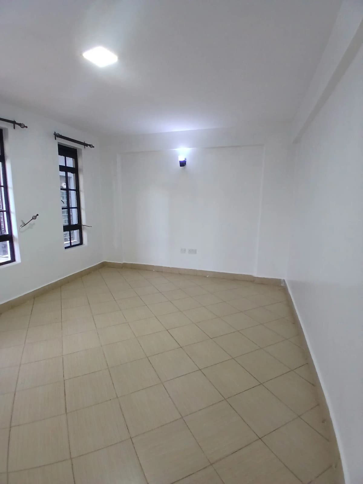 Spacious empty bedroom with tiled flooring and natural light