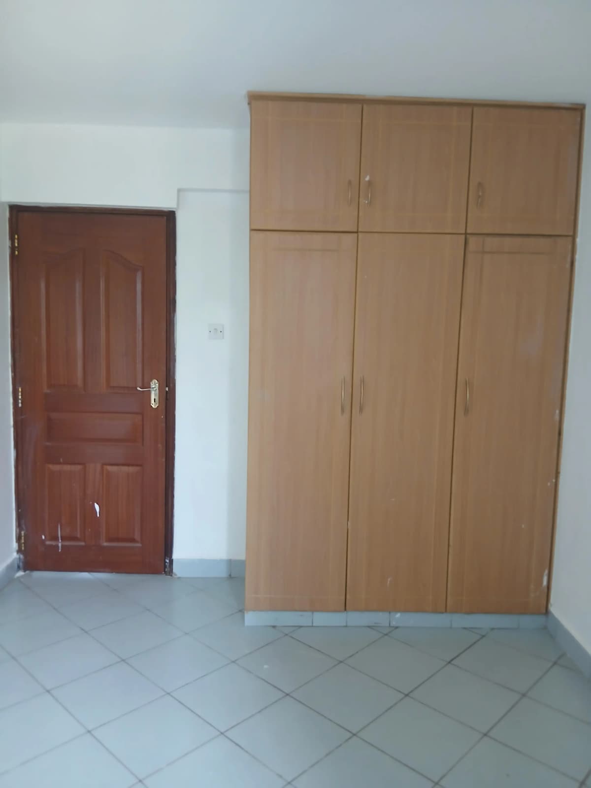 Bedroom with large wooden wardrobe and entry door