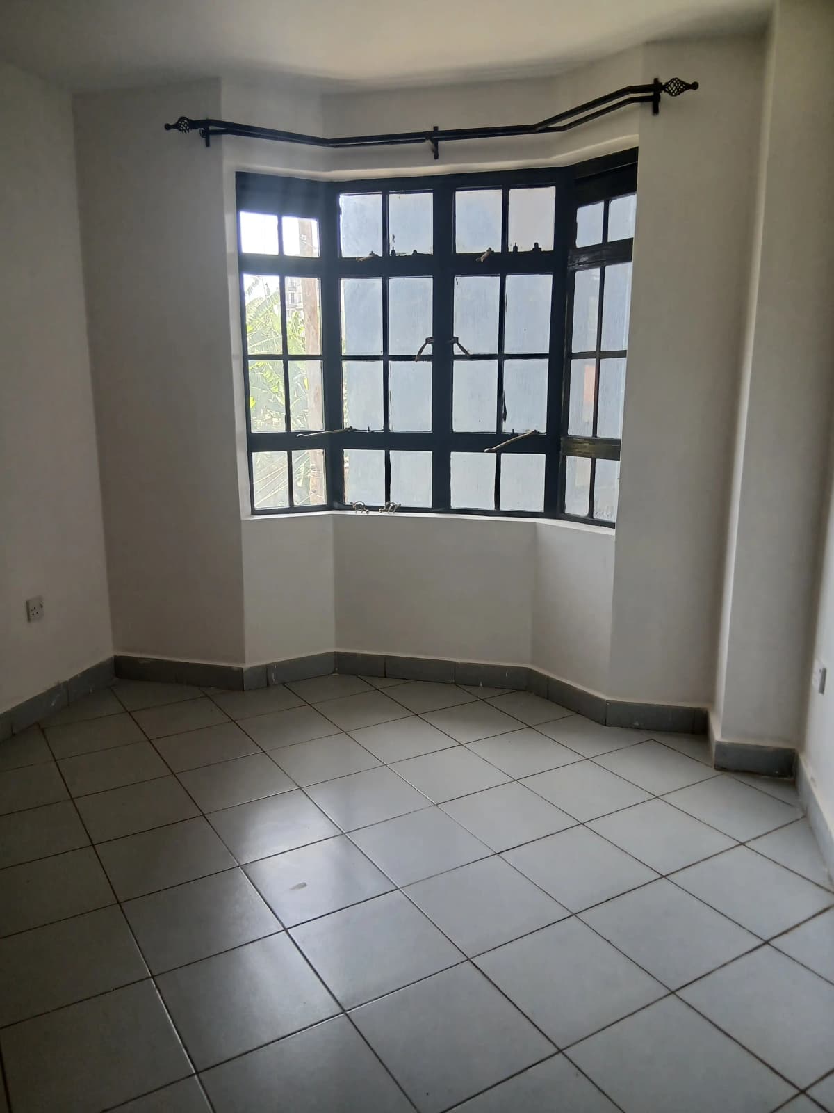 Bright bedroom with curved bay window and tile flooring