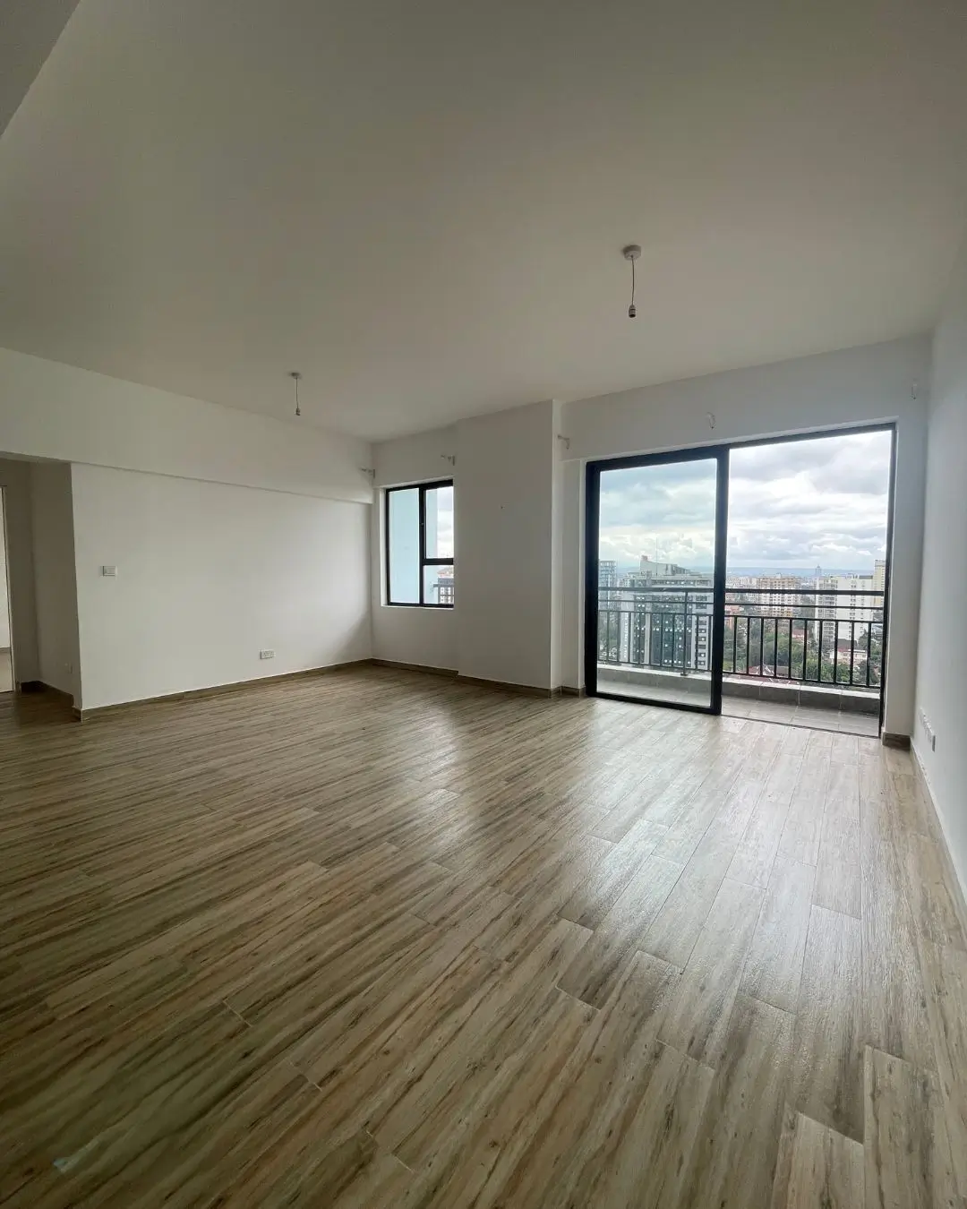 Spacious open-plan living area with wooden floors and city views
