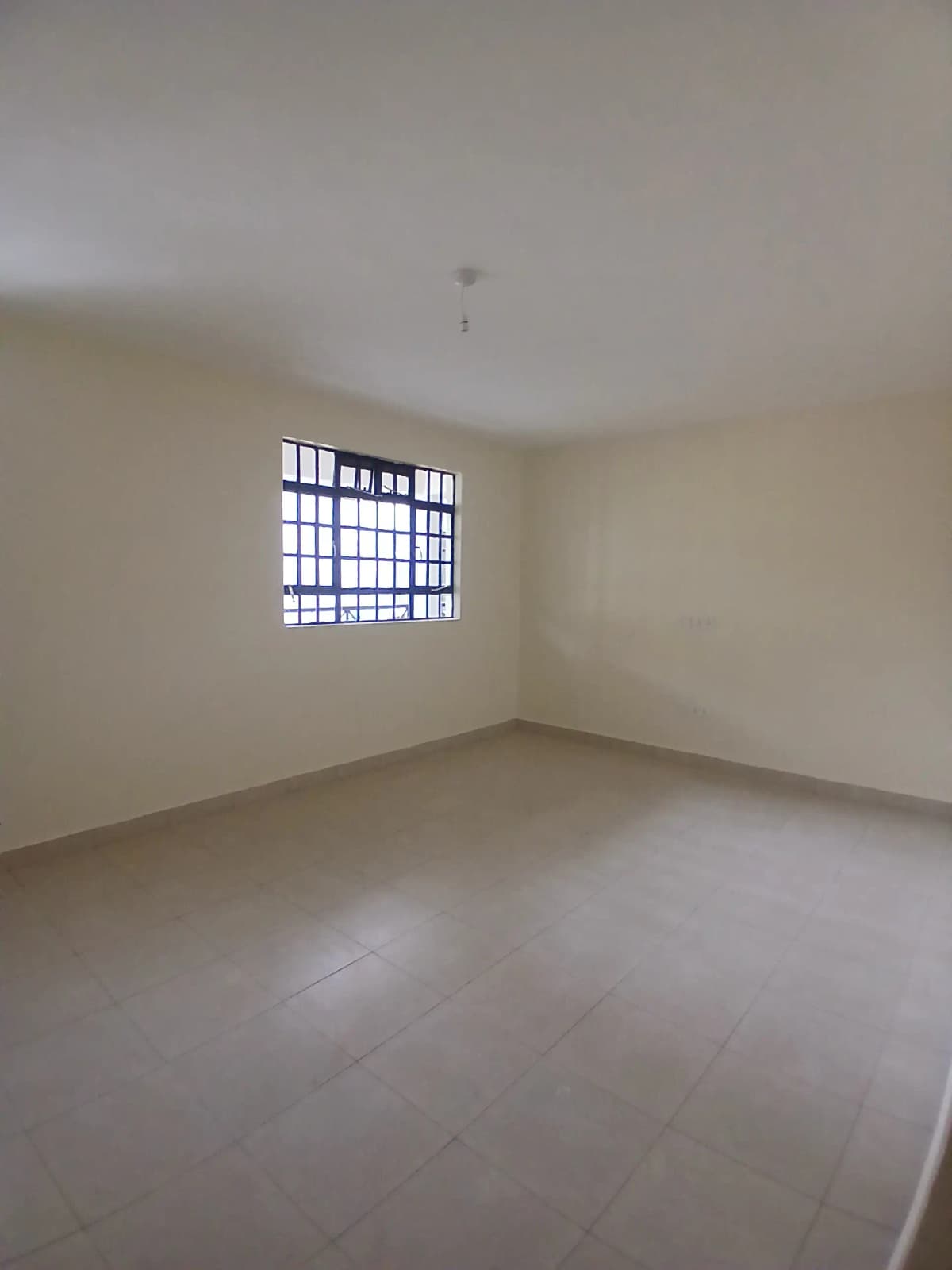 Empty bedroom with barred window and polished concrete floor