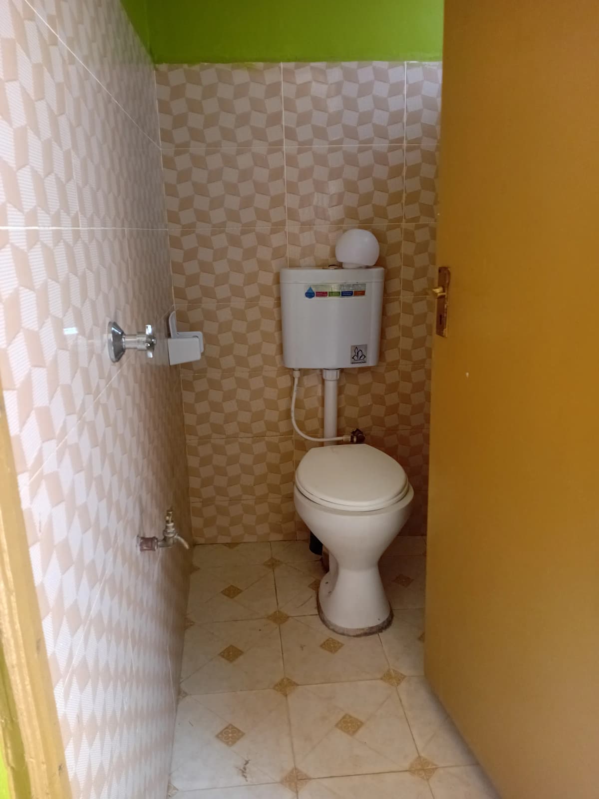 Compact toilet room with ceramic tiles and wall-mounted cistern