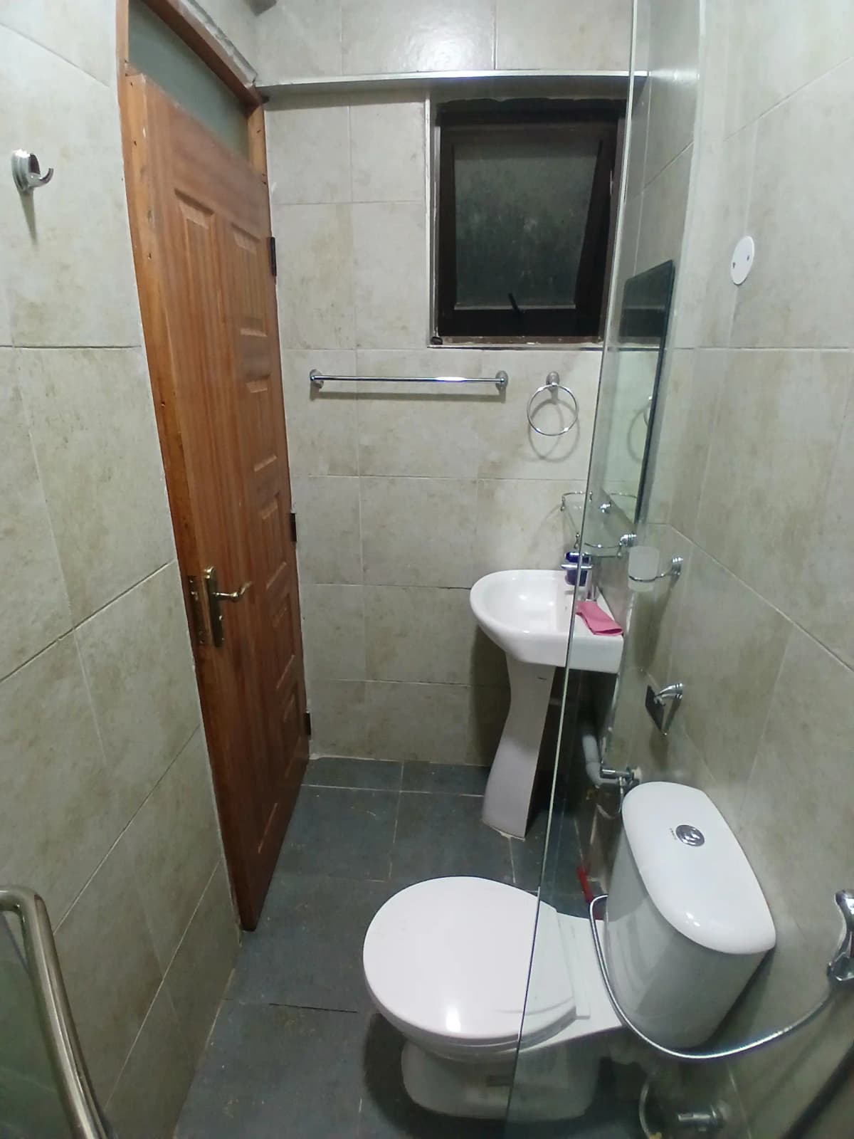 Compact bathroom with toilet, sink, and shower enclosure