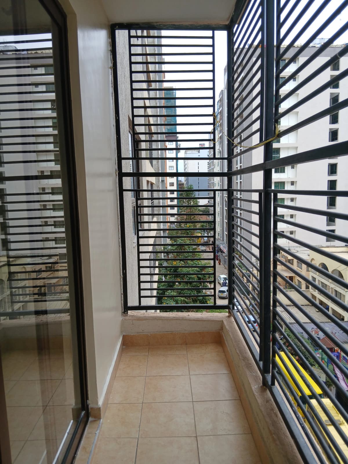 Narrow balcony with horizontal louver railings and city views