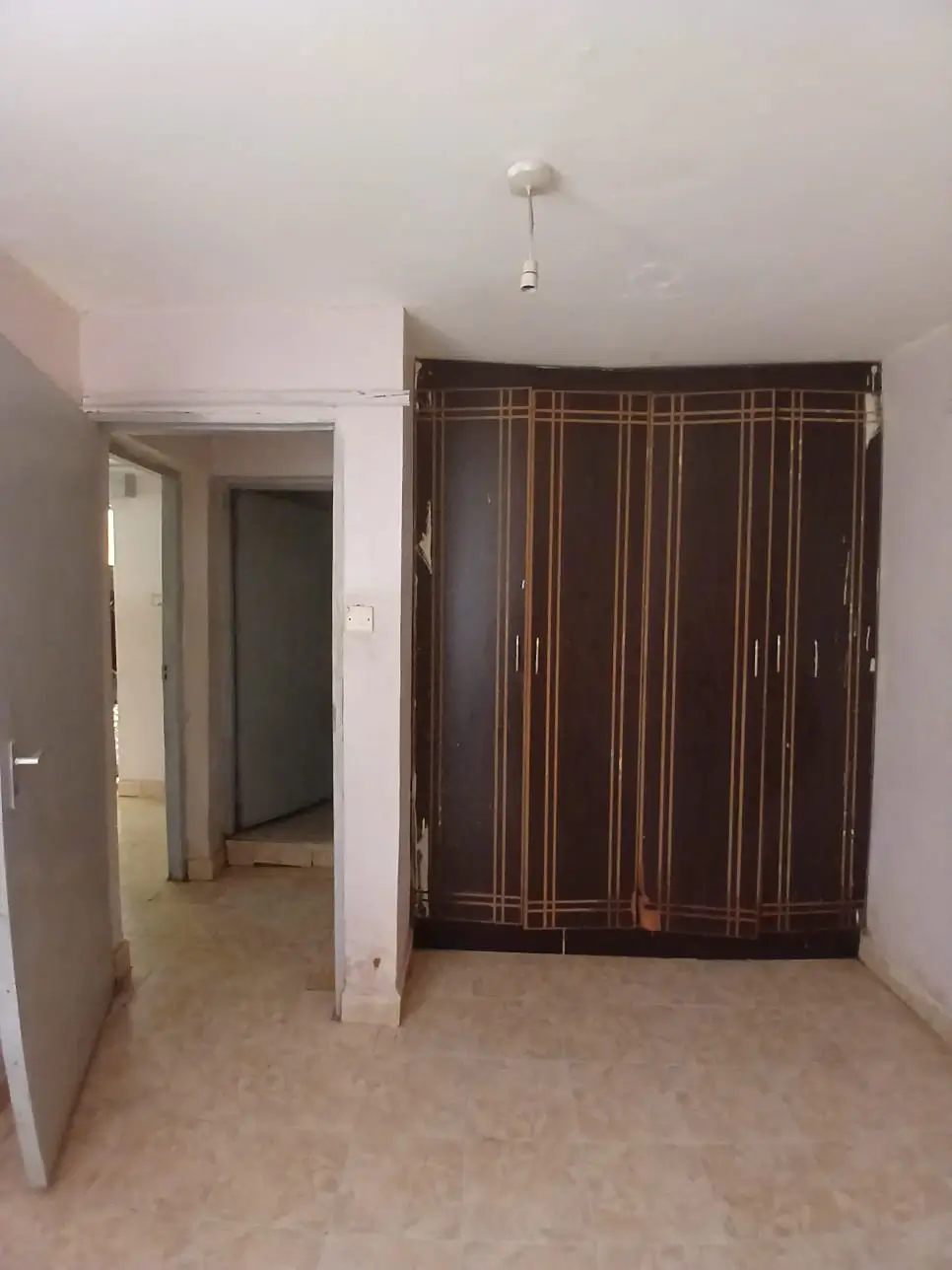 Empty bedroom with brown striped wardrobe and doorway