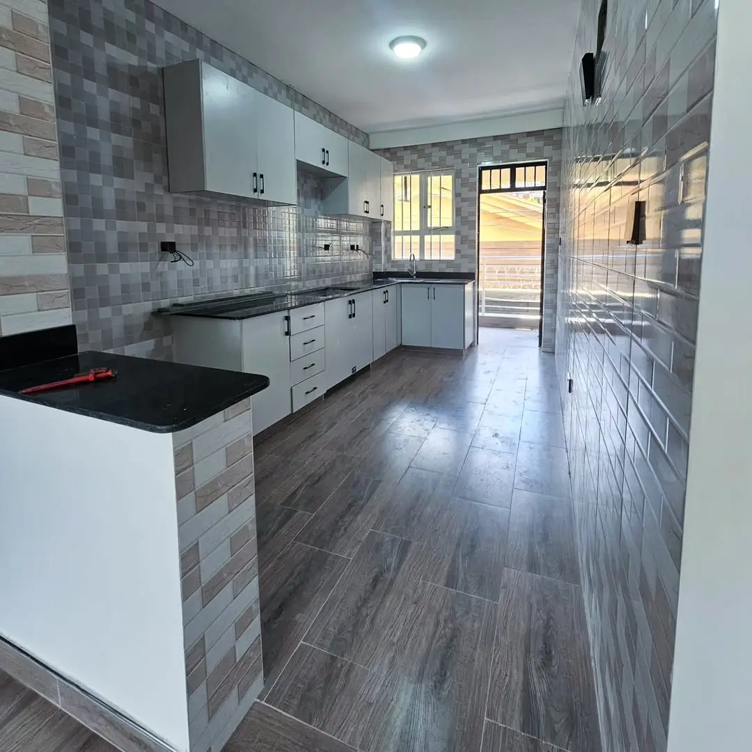 Modern kitchen with white cabinets, black countertops, tiled backsplash