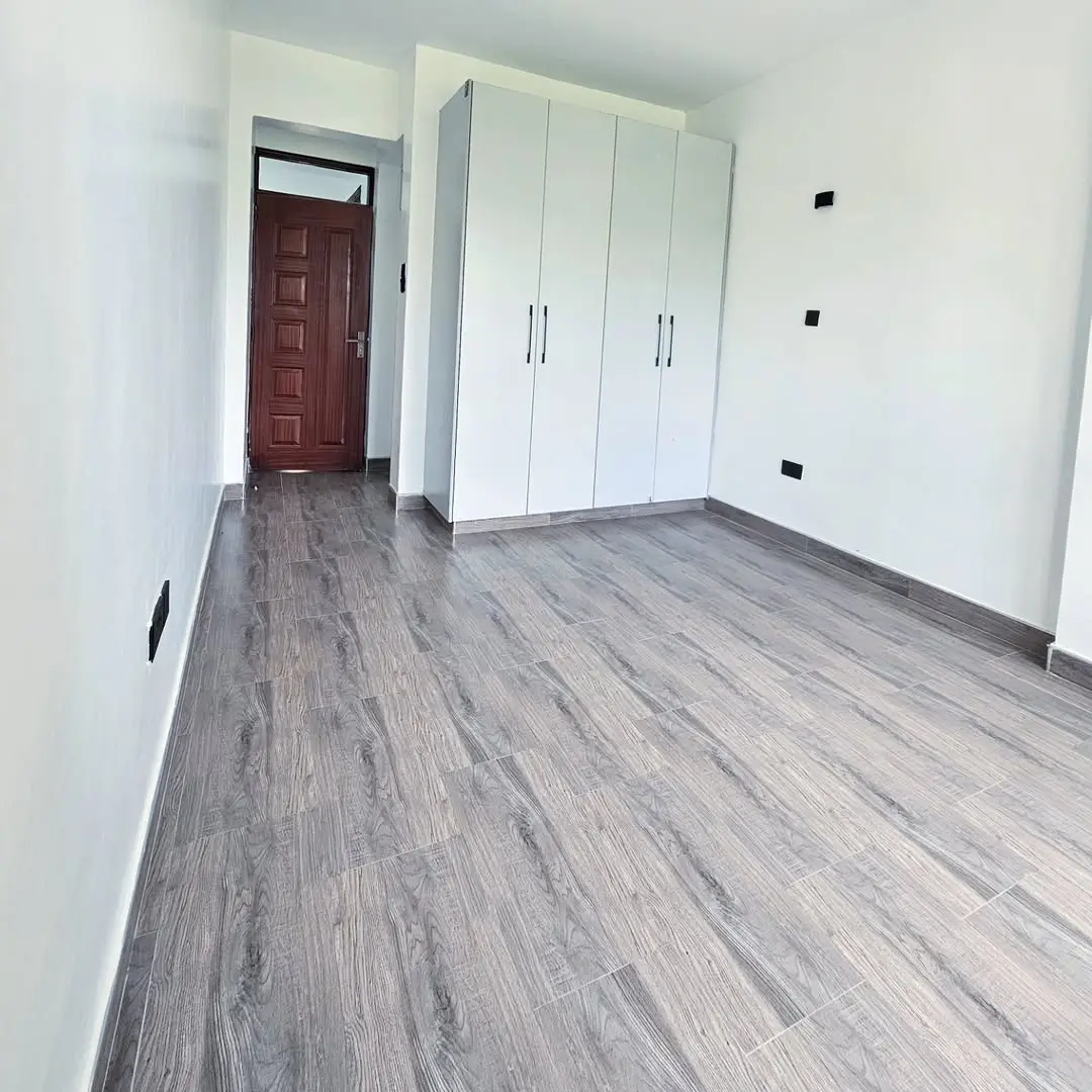 Spacious bedroom with built-in wardrobes and wooden flooring
