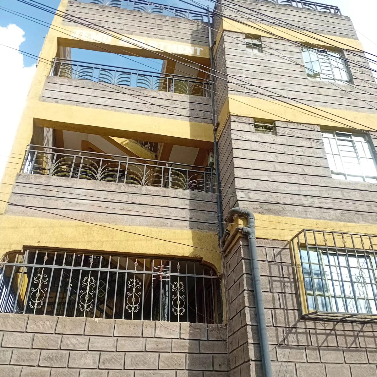 Multi-story residential building facade with yellow and gray finish