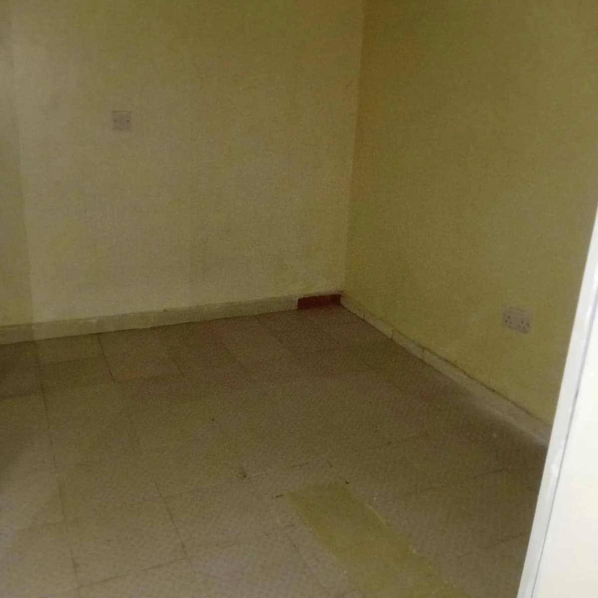 Empty bedroom with yellow walls and cement flooring