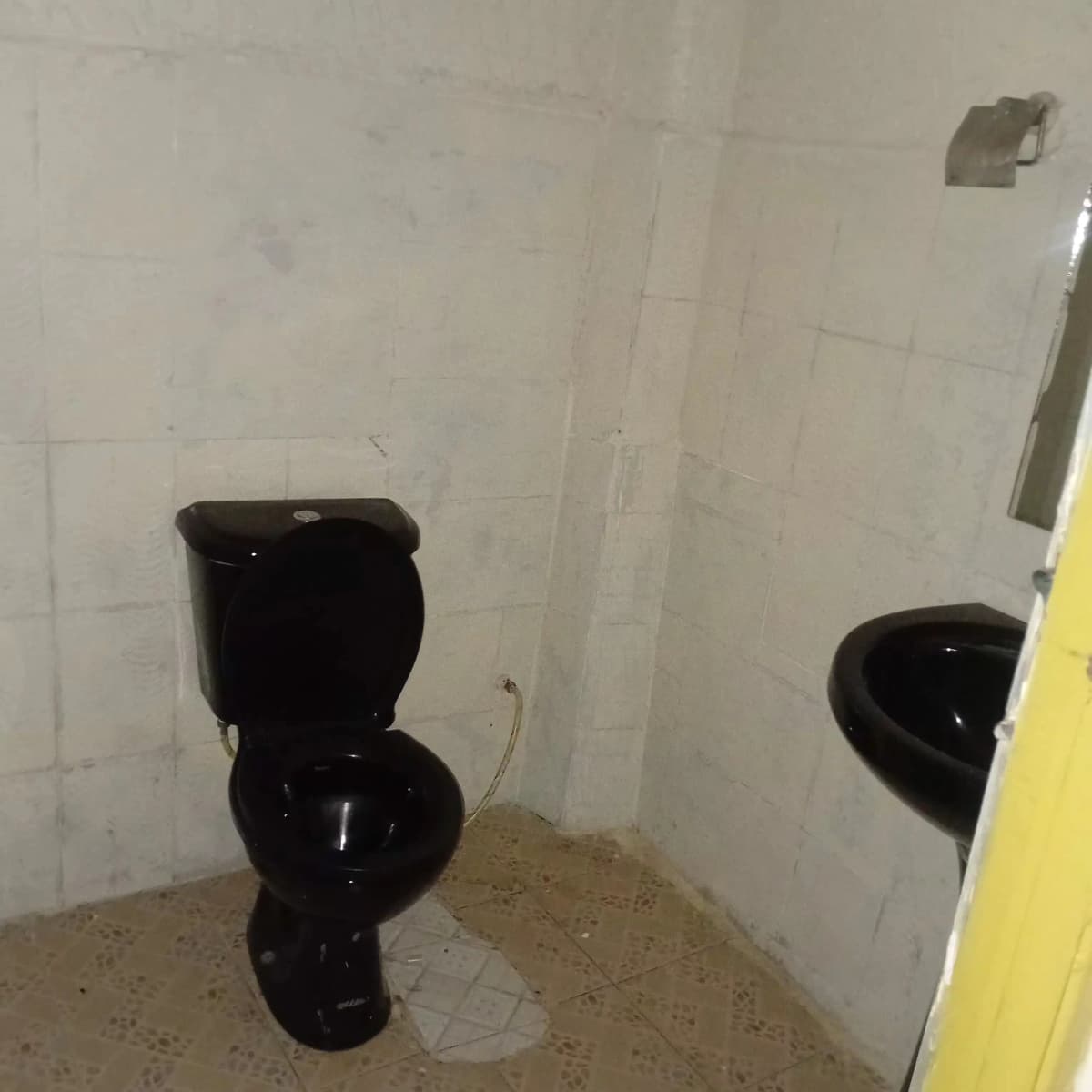 Basic bathroom with black toilet and tiled walls