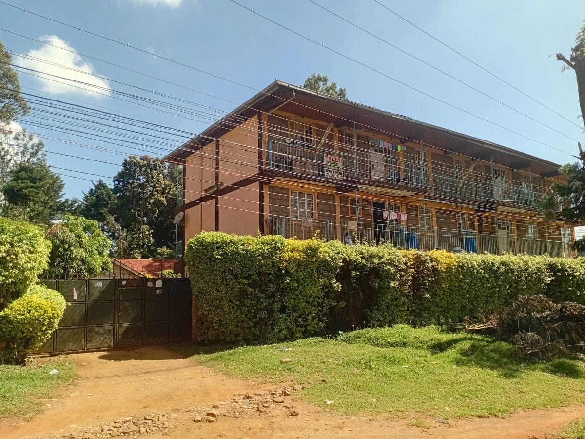 Two-story brick residential building with manicured hedge perimeter