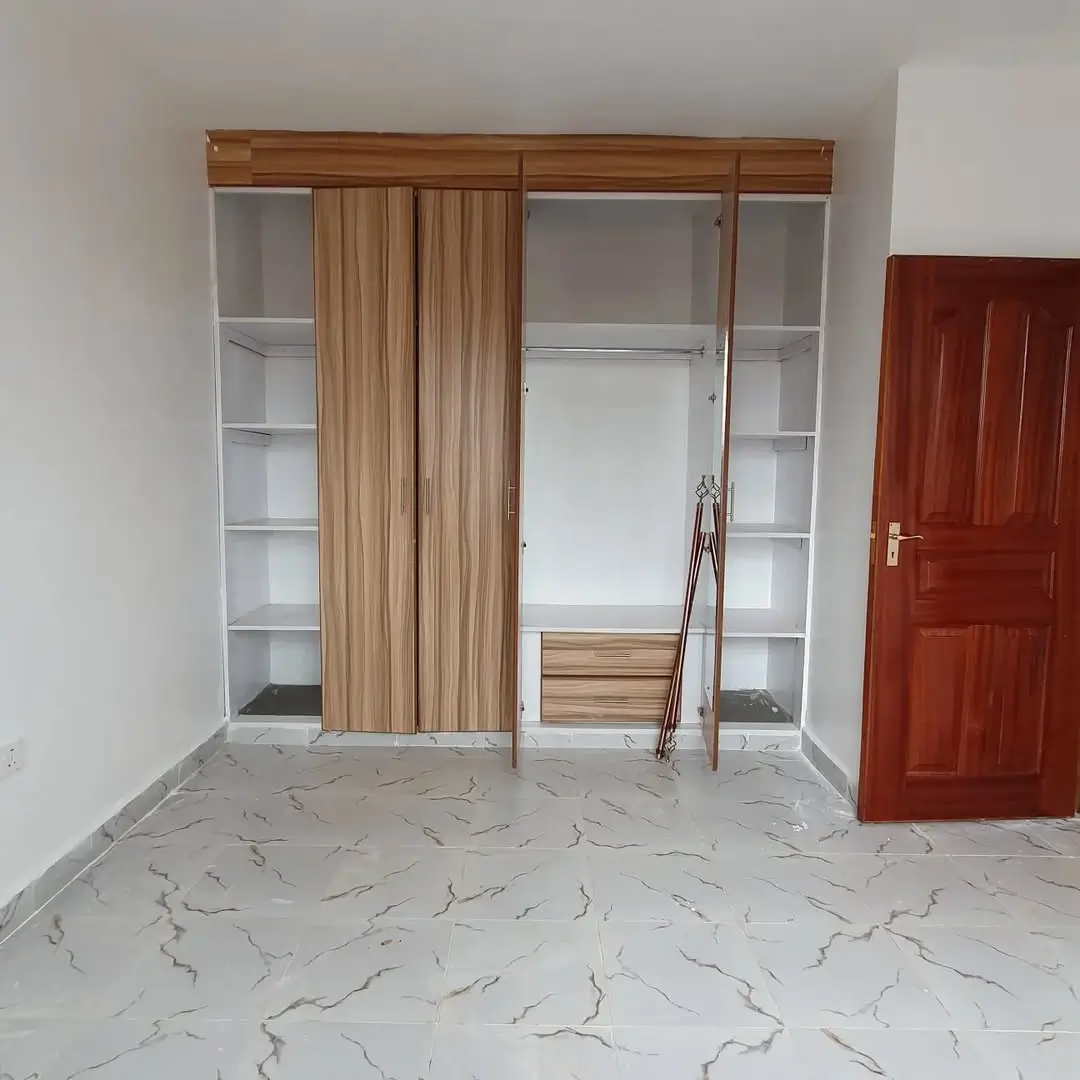 Spacious bedroom with built-in wooden wardrobe and marble flooring