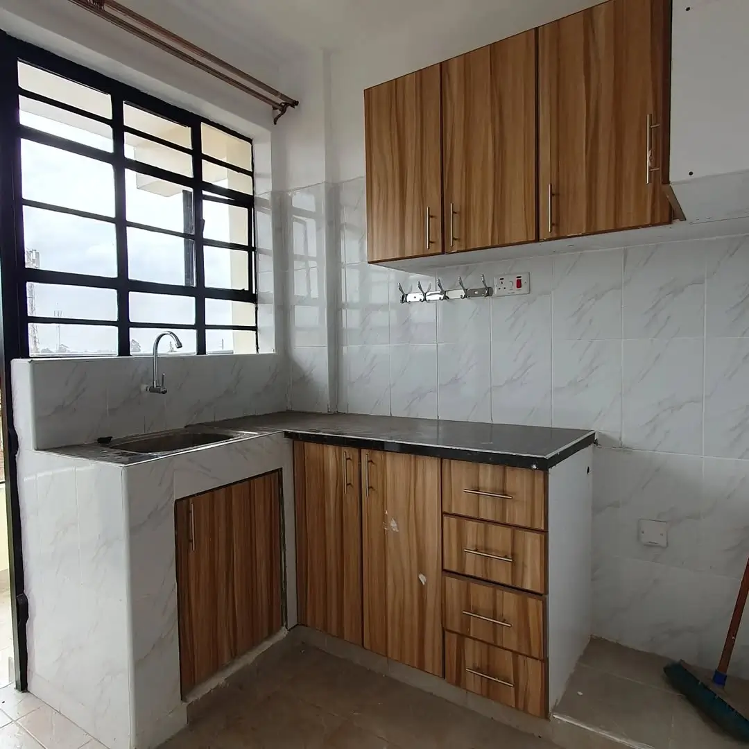 Compact kitchen with wooden cabinetry and stainless steel sink