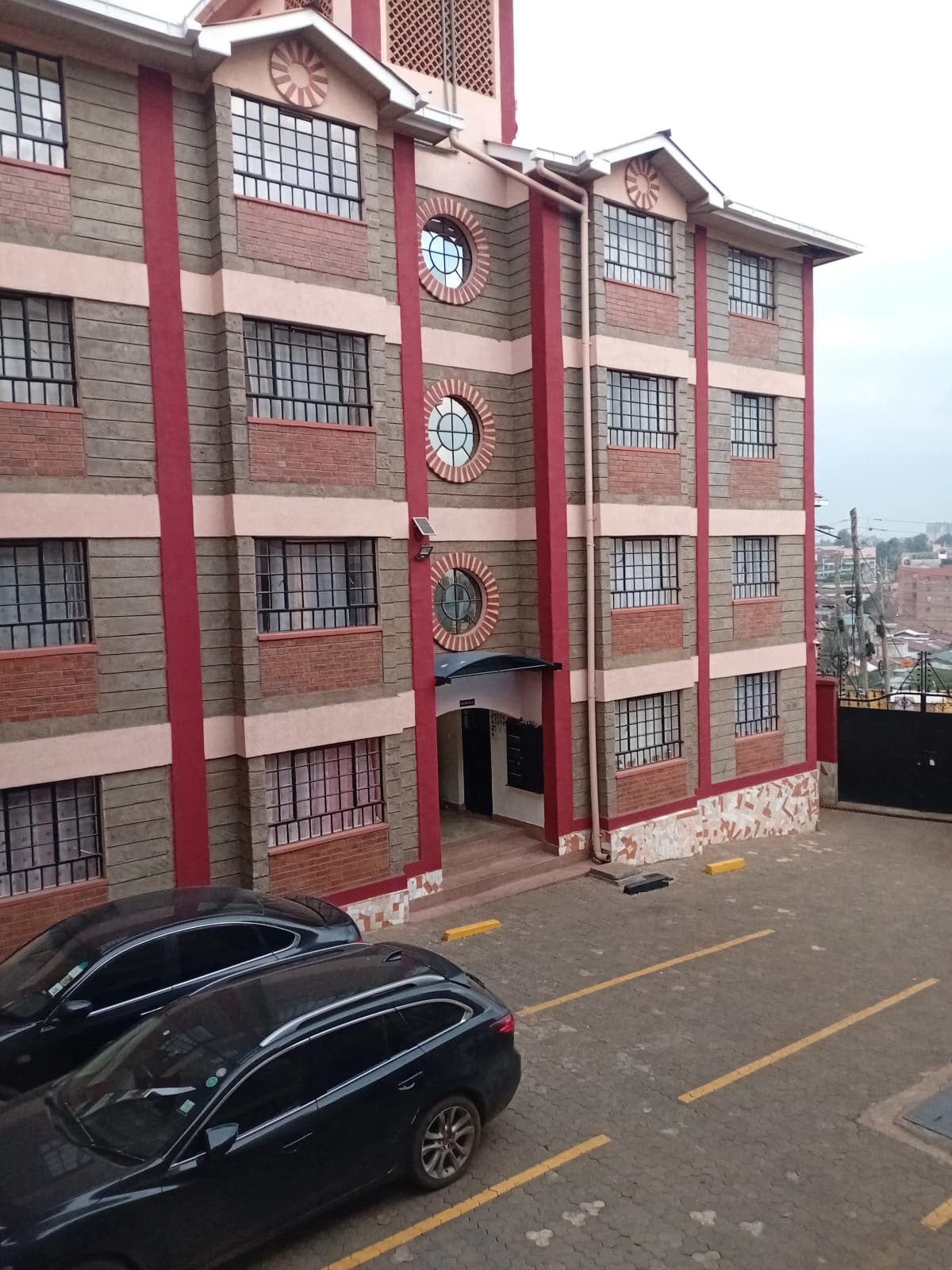 Red brick apartment building facade with ground-level parking bays