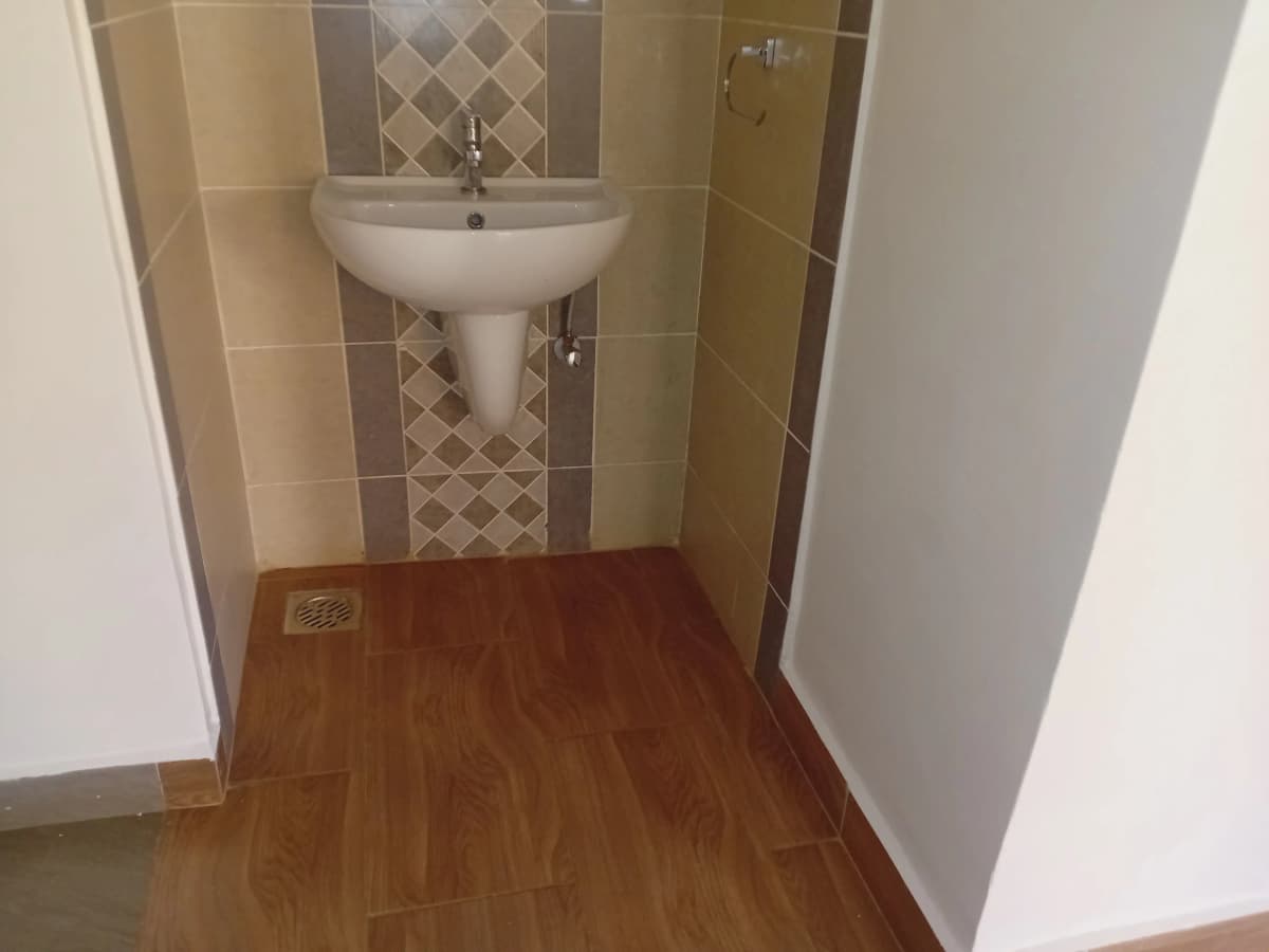 Compact bathroom with pedestal sink and tiled walls