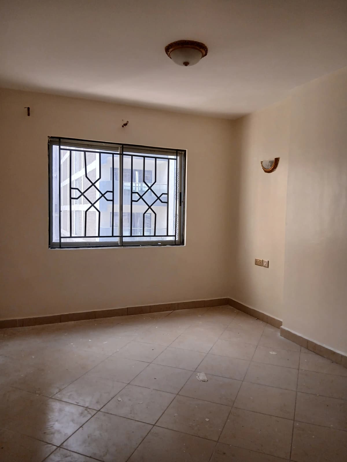 Empty bedroom with barred window and tiled flooring