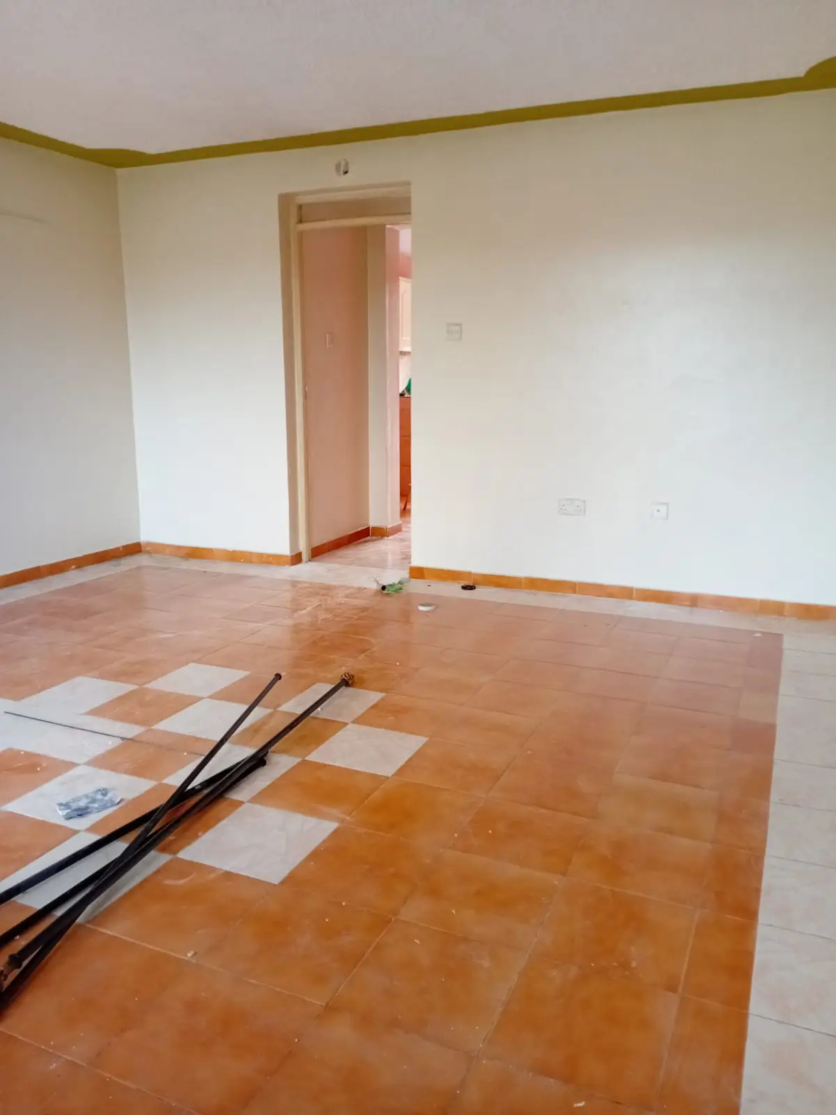 Empty living room with terracotta tile flooring, white walls