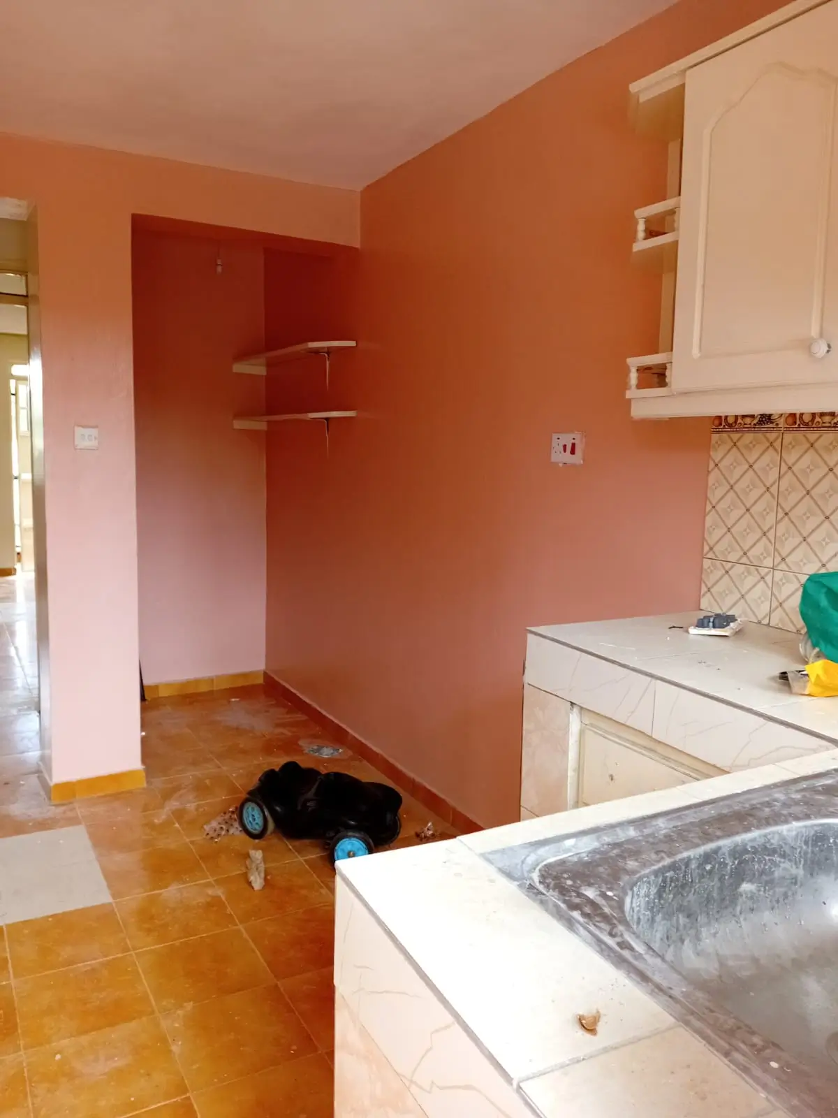 Orange kitchen with white cabinetry and open pantry space