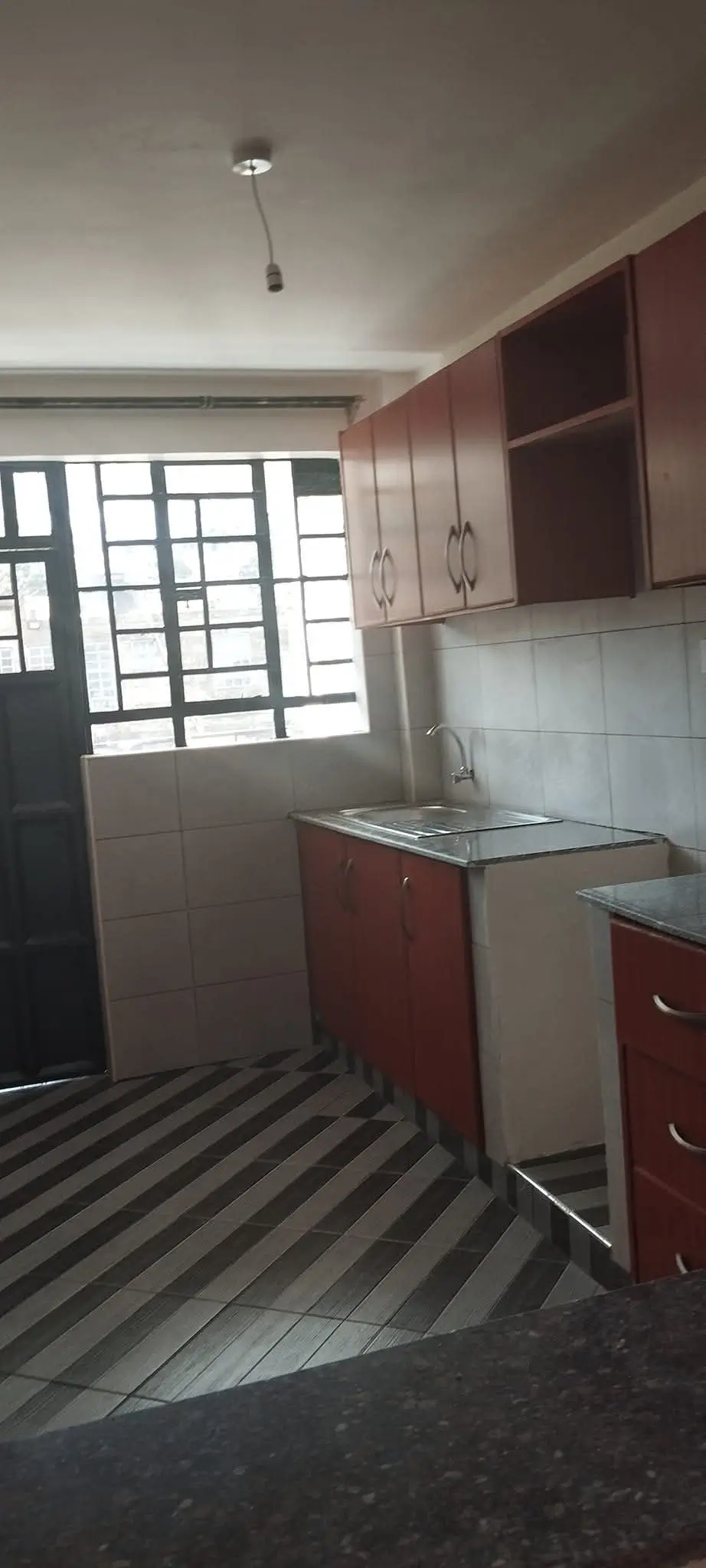 Compact kitchen with red cabinetry and window overlooking entrance