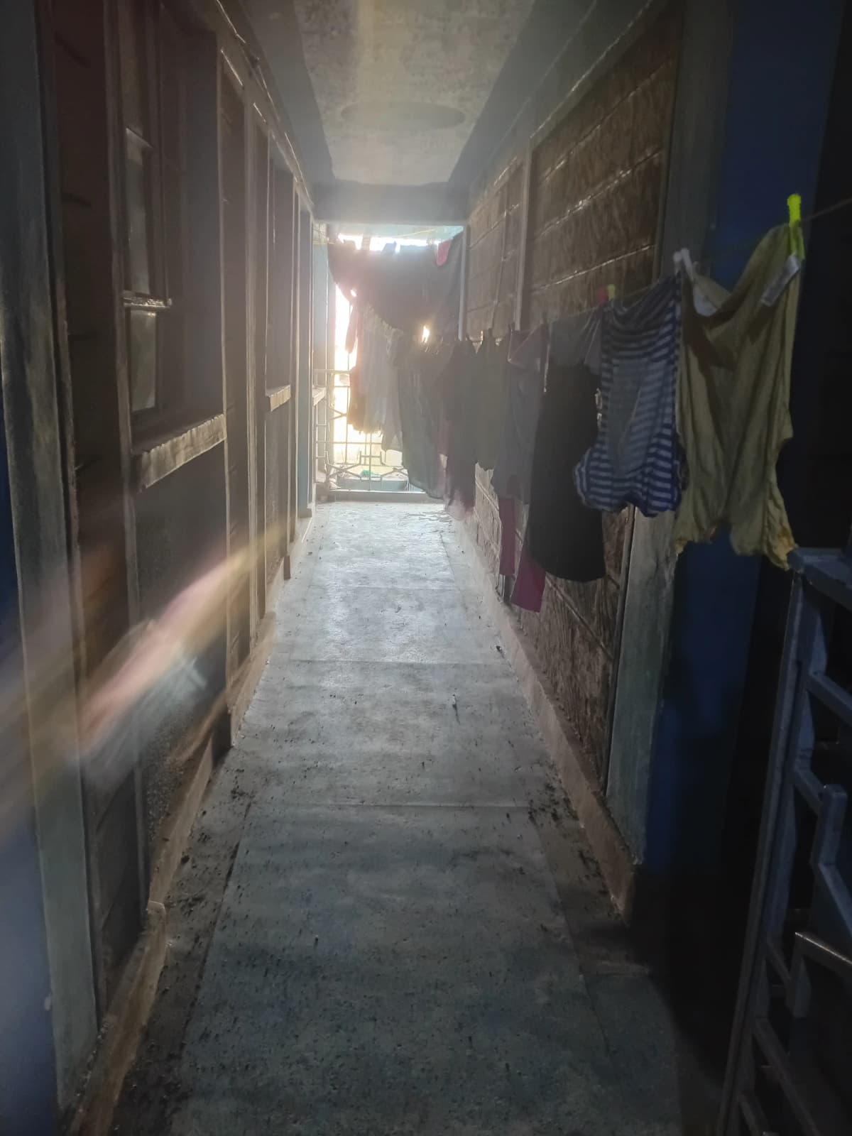 Narrow corridor with multiple doors and hanging laundry