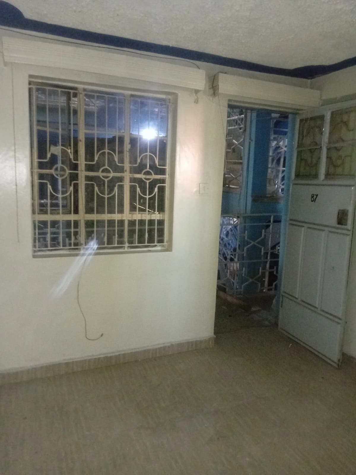 Empty living room with barred window and tiled flooring