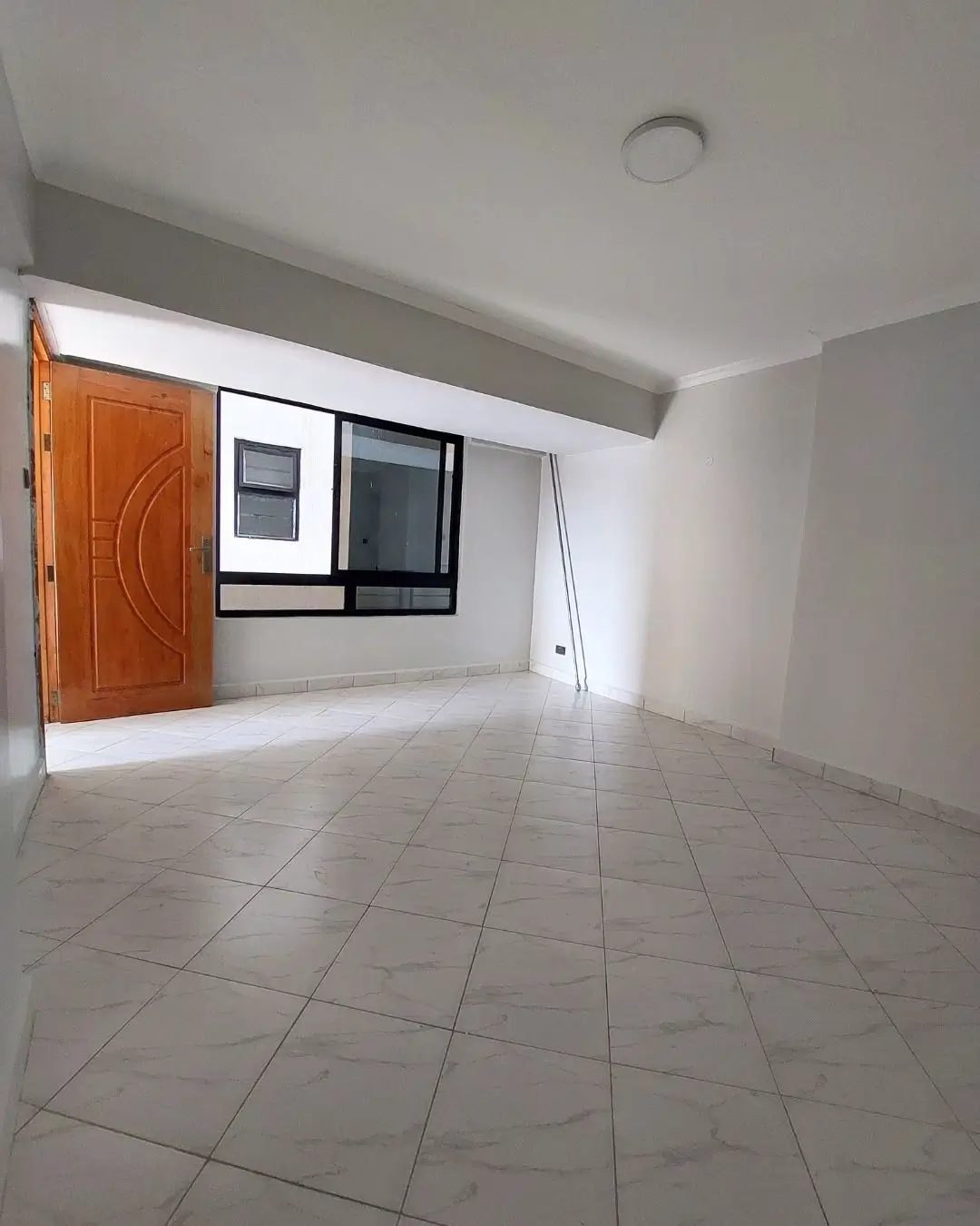 Bright empty living room with tiled flooring and large windows