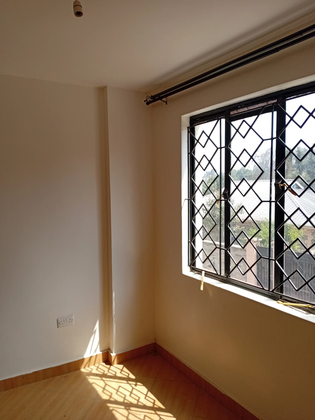 Bright bedroom with wooden floor and security window grilles